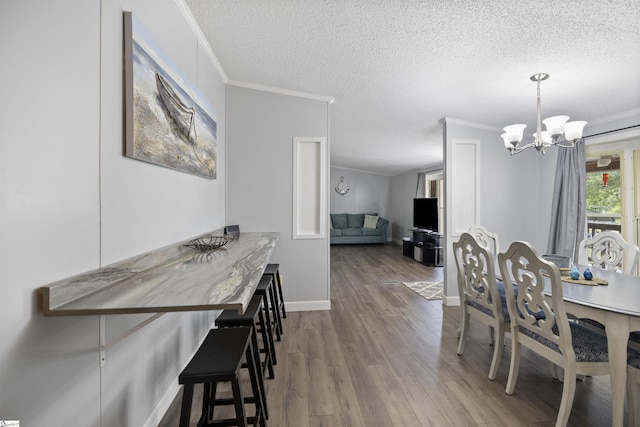 dining room featuring crown molding, wood-type flooring, a textured ceiling, and an inviting chandelier