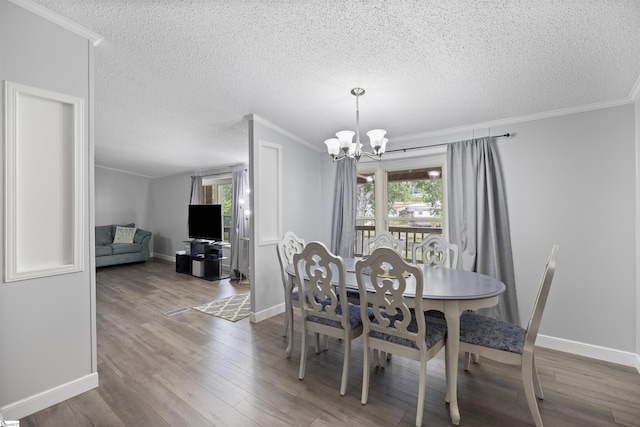 dining room featuring wood-type flooring, a chandelier, a textured ceiling, and ornamental molding