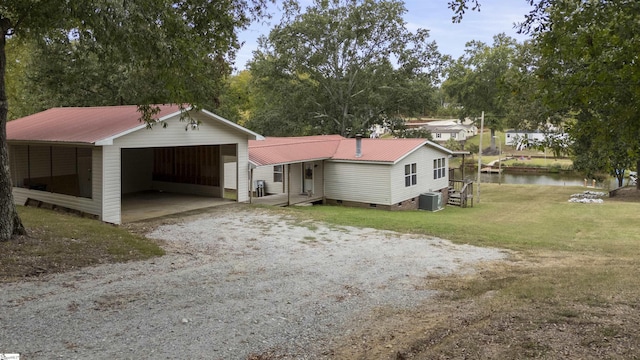 view of front facade with an outdoor structure, a water view, central AC, a front yard, and a garage