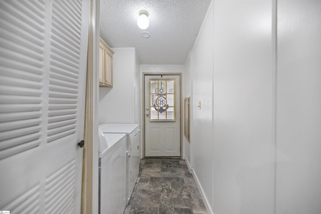 clothes washing area with cabinets, a textured ceiling, and washing machine and clothes dryer