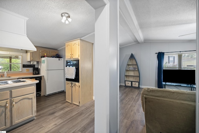 kitchen featuring black oven, light wood-type flooring, vaulted ceiling, and white refrigerator