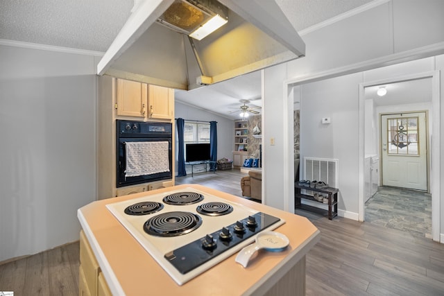 kitchen with black oven, white electric stovetop, light brown cabinets, and a textured ceiling