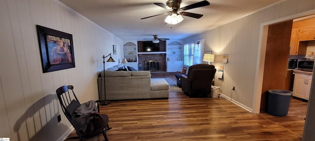 living room with built in shelves, ceiling fan, a fireplace, and dark hardwood / wood-style floors