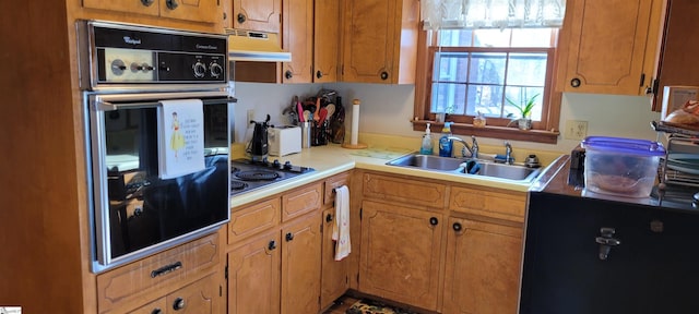 kitchen featuring black oven, cooktop, sink, and range hood