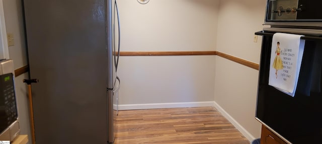 interior space with hardwood / wood-style flooring, wall oven, and stainless steel refrigerator