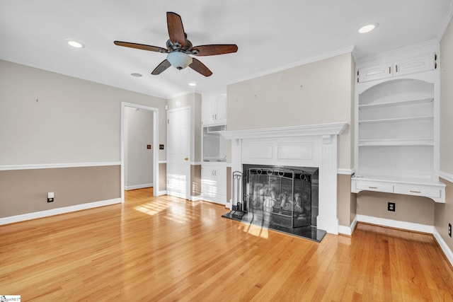 unfurnished living room featuring ceiling fan, built in shelves, crown molding, and light hardwood / wood-style flooring