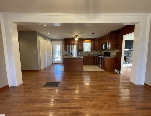 kitchen with a center island, backsplash, stainless steel appliances, and light hardwood / wood-style flooring