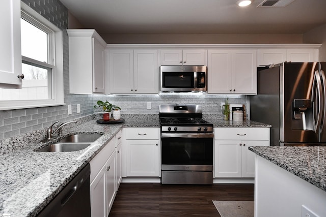 kitchen with sink, stainless steel appliances, light stone counters, dark hardwood / wood-style flooring, and white cabinets