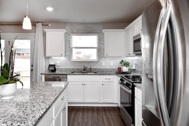 kitchen with light stone countertops, stainless steel appliances, sink, pendant lighting, and white cabinets