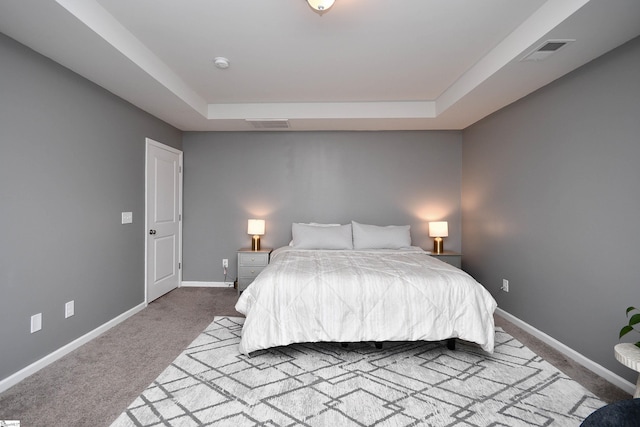 bedroom with carpet floors and a tray ceiling