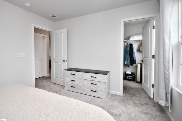 bedroom with light carpet, a walk in closet, and a closet