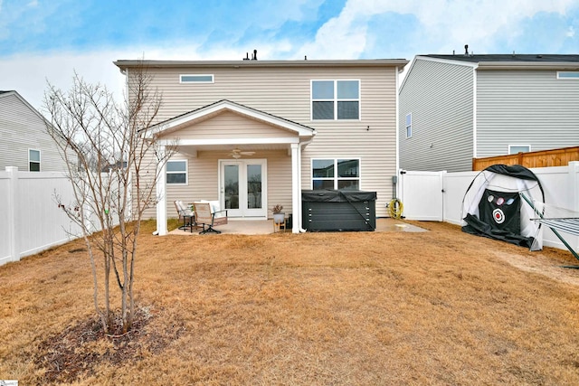 back of property featuring french doors, ceiling fan, a patio, a hot tub, and a lawn