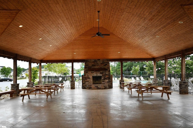 unfurnished sunroom with vaulted ceiling, ceiling fan, wood ceiling, and an outdoor stone fireplace