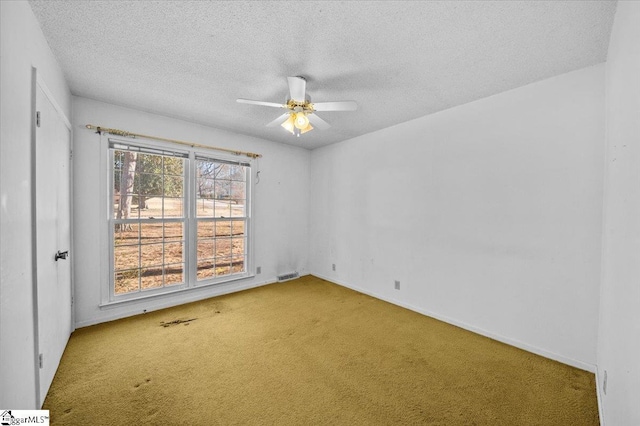 empty room with carpet flooring, ceiling fan, and a textured ceiling