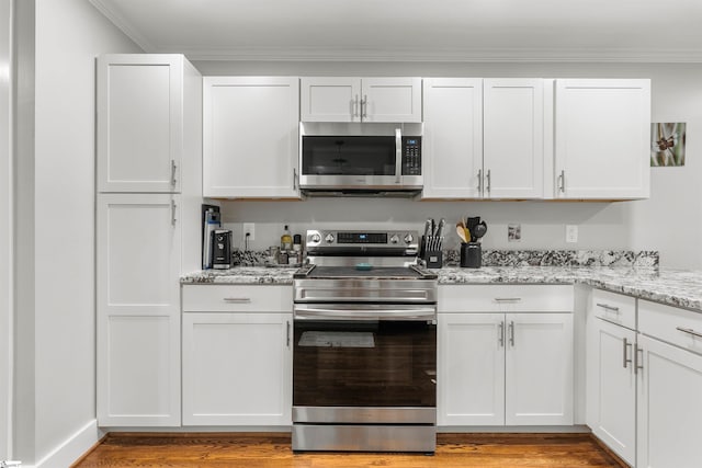 kitchen with white cabinets, appliances with stainless steel finishes, light hardwood / wood-style floors, and light stone countertops