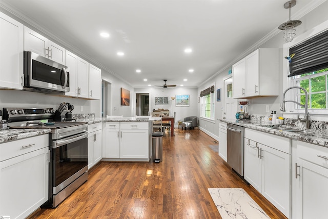 kitchen with white cabinetry, sink, ceiling fan, light stone countertops, and appliances with stainless steel finishes