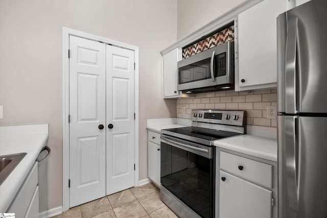 kitchen with white cabinets, light tile patterned flooring, stainless steel appliances, and tasteful backsplash