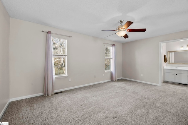 unfurnished bedroom with a textured ceiling, ceiling fan, light carpet, and connected bathroom