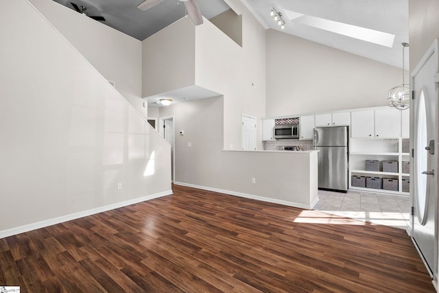 kitchen with white cabinets, ceiling fan with notable chandelier, stainless steel appliances, and hardwood / wood-style flooring