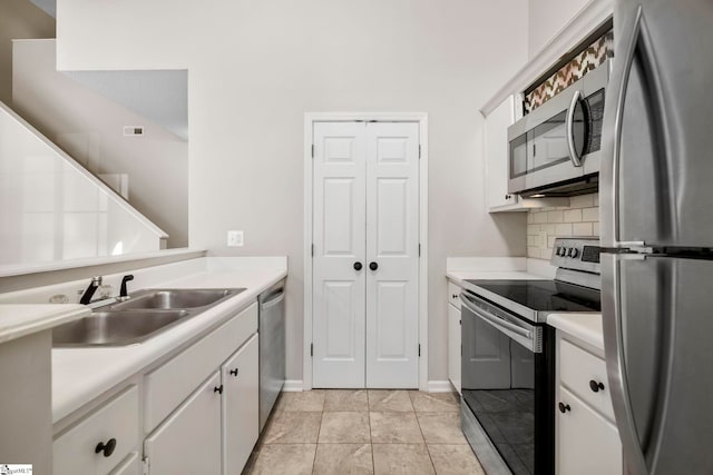 kitchen featuring backsplash, stainless steel appliances, sink, light tile patterned floors, and white cabinetry