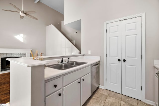 kitchen with ceiling fan, sink, stainless steel dishwasher, kitchen peninsula, and a fireplace