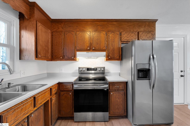 kitchen featuring sink, light hardwood / wood-style flooring, ornamental molding, and appliances with stainless steel finishes