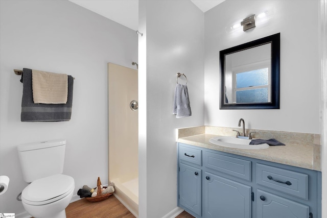 bathroom with a shower, hardwood / wood-style floors, vanity, and toilet