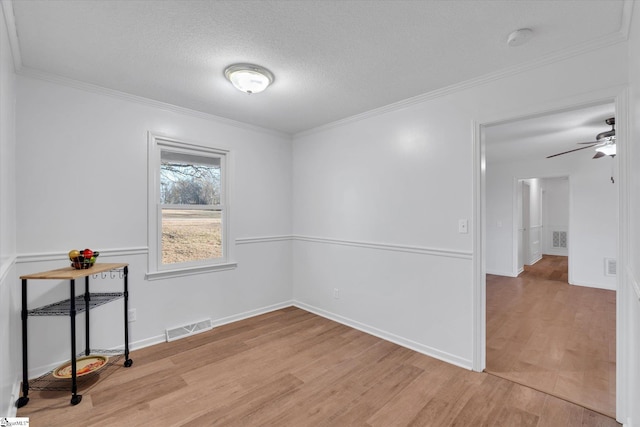 empty room with ceiling fan, crown molding, a textured ceiling, and light hardwood / wood-style flooring