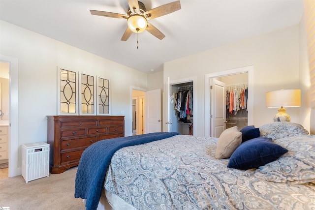 bedroom featuring ensuite bath, ceiling fan, a walk in closet, light carpet, and a closet