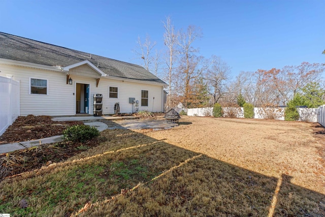 back of house with a lawn and a fire pit