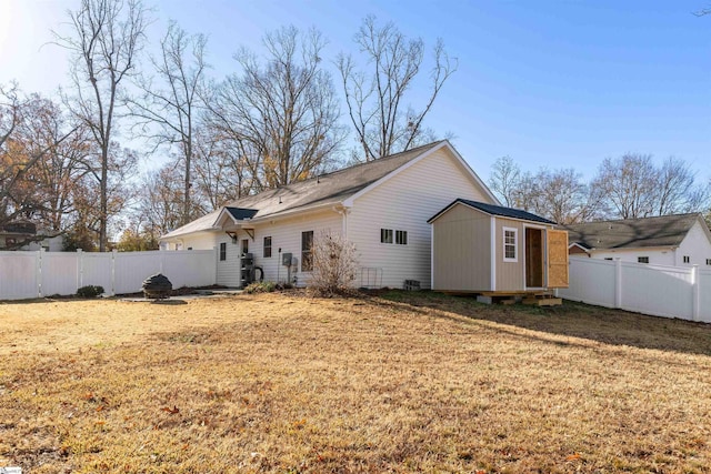 rear view of property featuring a storage shed and a lawn