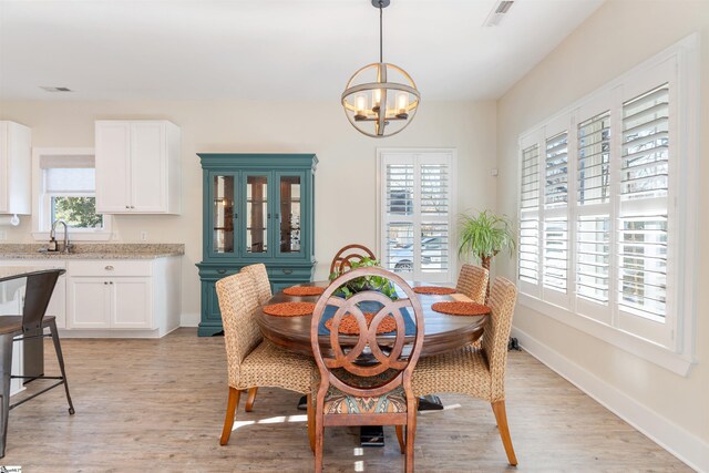 dining area featuring plenty of natural light, sink, light hardwood / wood-style flooring, and a chandelier