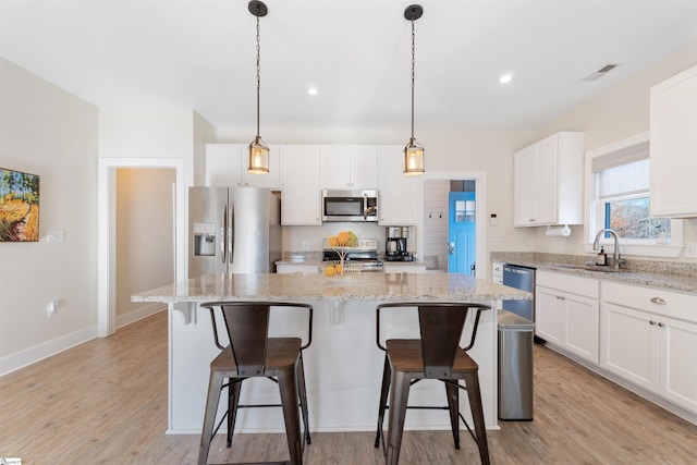 kitchen with white cabinets, a center island, sink, and appliances with stainless steel finishes