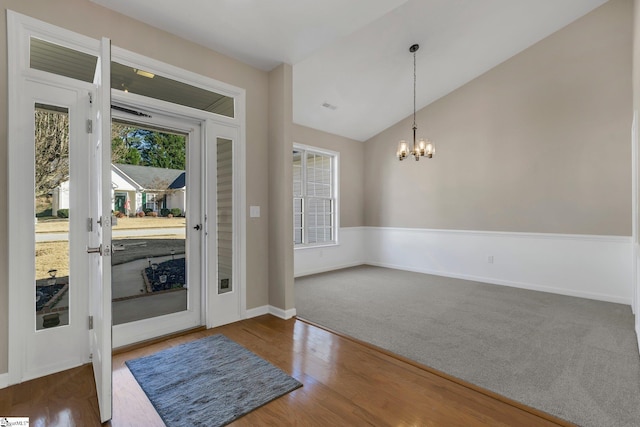 foyer entrance featuring vaulted ceiling, an inviting chandelier, and dark wood-type flooring