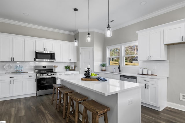 kitchen with decorative light fixtures, a kitchen island, white cabinetry, and appliances with stainless steel finishes