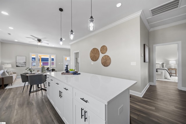 kitchen with crown molding, ceiling fan, decorative light fixtures, a kitchen island, and white cabinetry