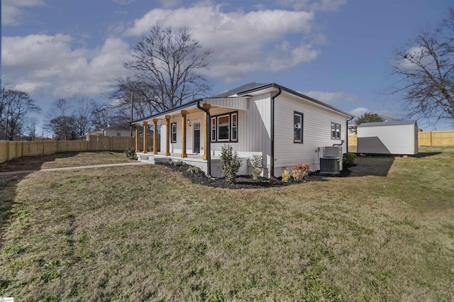 view of side of home featuring covered porch, a yard, a storage shed, and central air condition unit