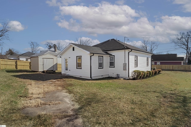 rear view of house featuring a yard and a storage shed