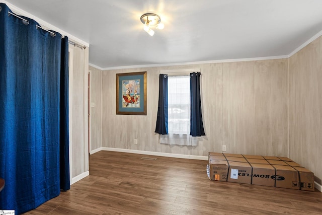 empty room with wooden walls, dark hardwood / wood-style flooring, and crown molding