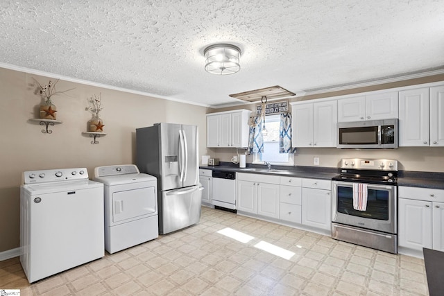 kitchen with appliances with stainless steel finishes, independent washer and dryer, white cabinetry, and crown molding