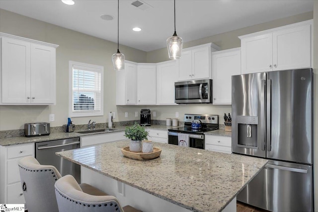 kitchen with hanging light fixtures, sink, a center island, and stainless steel appliances