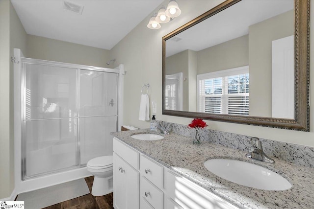 bathroom featuring wood-type flooring, vanity, toilet, and a shower with door