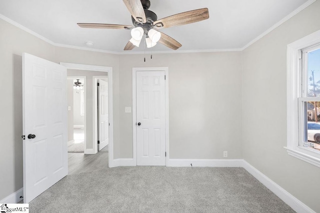 unfurnished bedroom with light carpet, multiple windows, ceiling fan, and ornamental molding