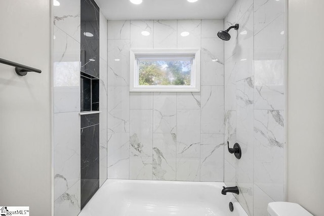 bathroom featuring toilet and tiled shower / bath