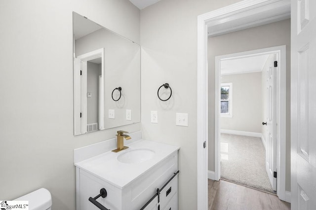 bathroom with hardwood / wood-style flooring, vanity, and toilet