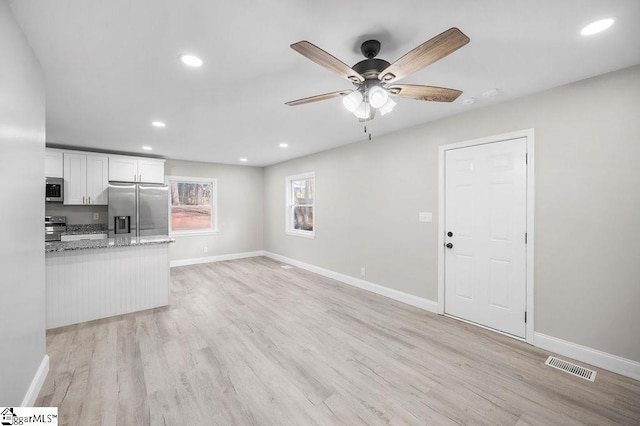 kitchen with white cabinets, light hardwood / wood-style flooring, ceiling fan, light stone countertops, and stainless steel appliances