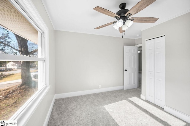 unfurnished bedroom featuring multiple windows, ceiling fan, a closet, and light carpet