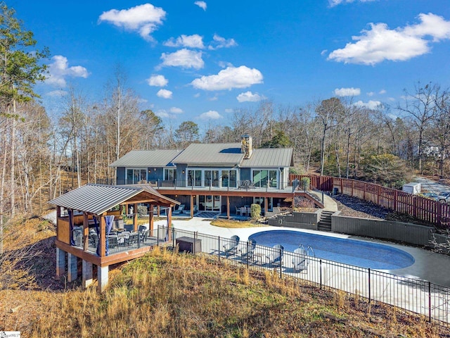 rear view of property with a pool side deck and a patio