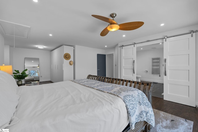 bedroom featuring a barn door, dark hardwood / wood-style floors, and ceiling fan