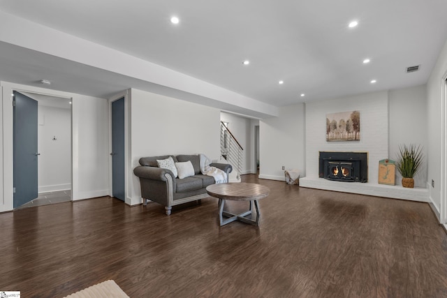 living room featuring dark hardwood / wood-style flooring and a brick fireplace